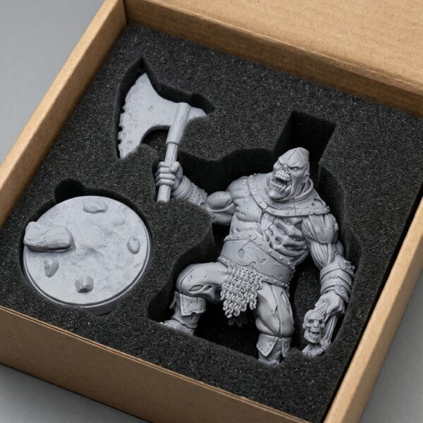 Unpainted miniature figure of a warrior with an axe and shield in a foam box.